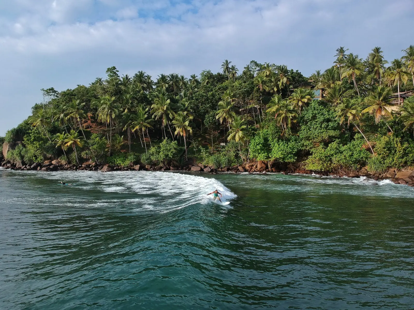 A man surfs in Sri Lanka over looking the jungle.
