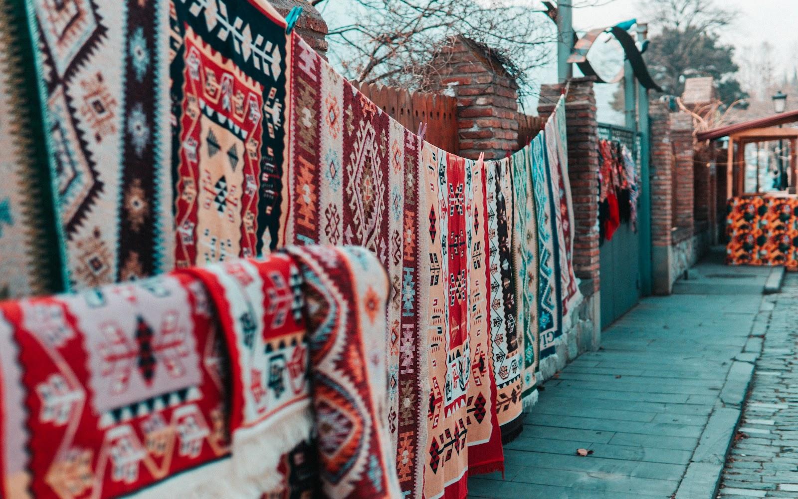 Colourful traditional woven carpets hanging up against a wall