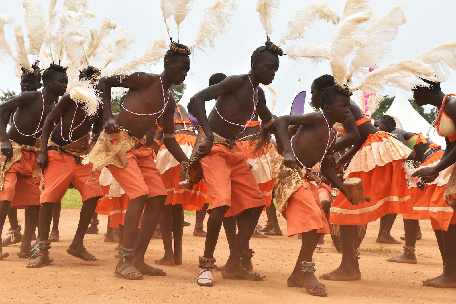 Young Ugandan men dancing and wearing traditional clothing and headdresses. 