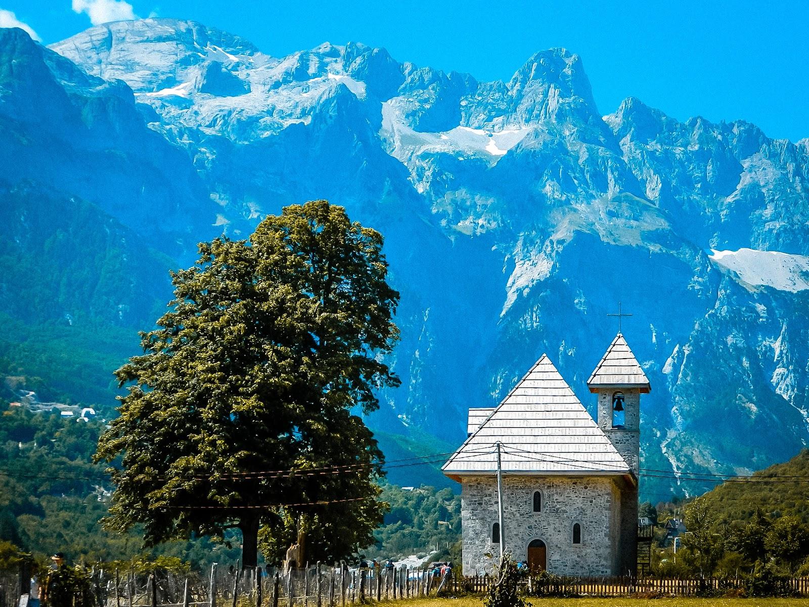 a small church in front of the peaks of the Balkan trail hiking. 
