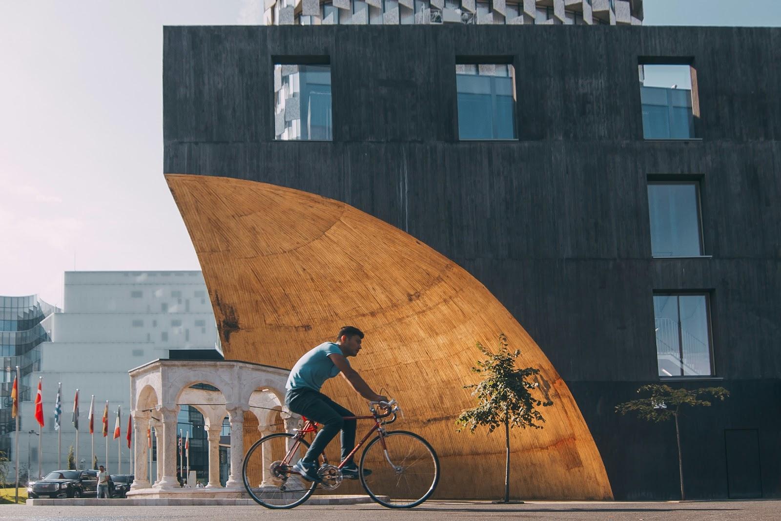 a man cycling in front of The Kapllan Pasha Tomb. A Muslim Türbe of Albania, located in the center of Tirana.