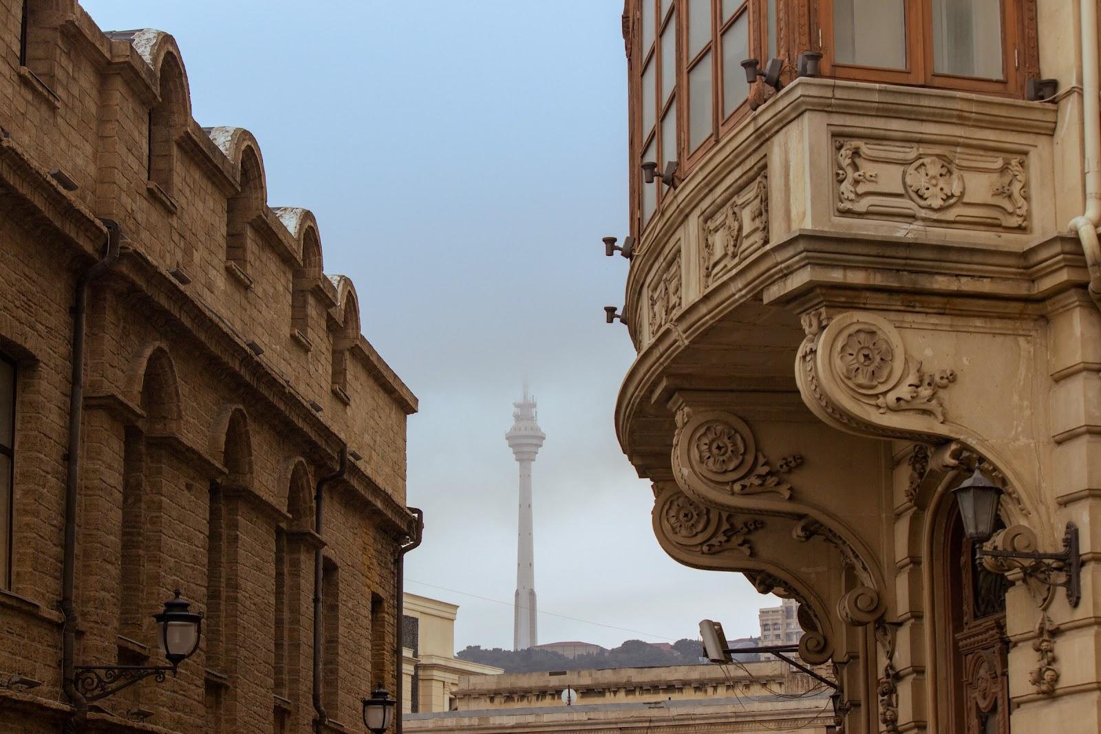 An ornate building with tall modern communications tower in the distance. 