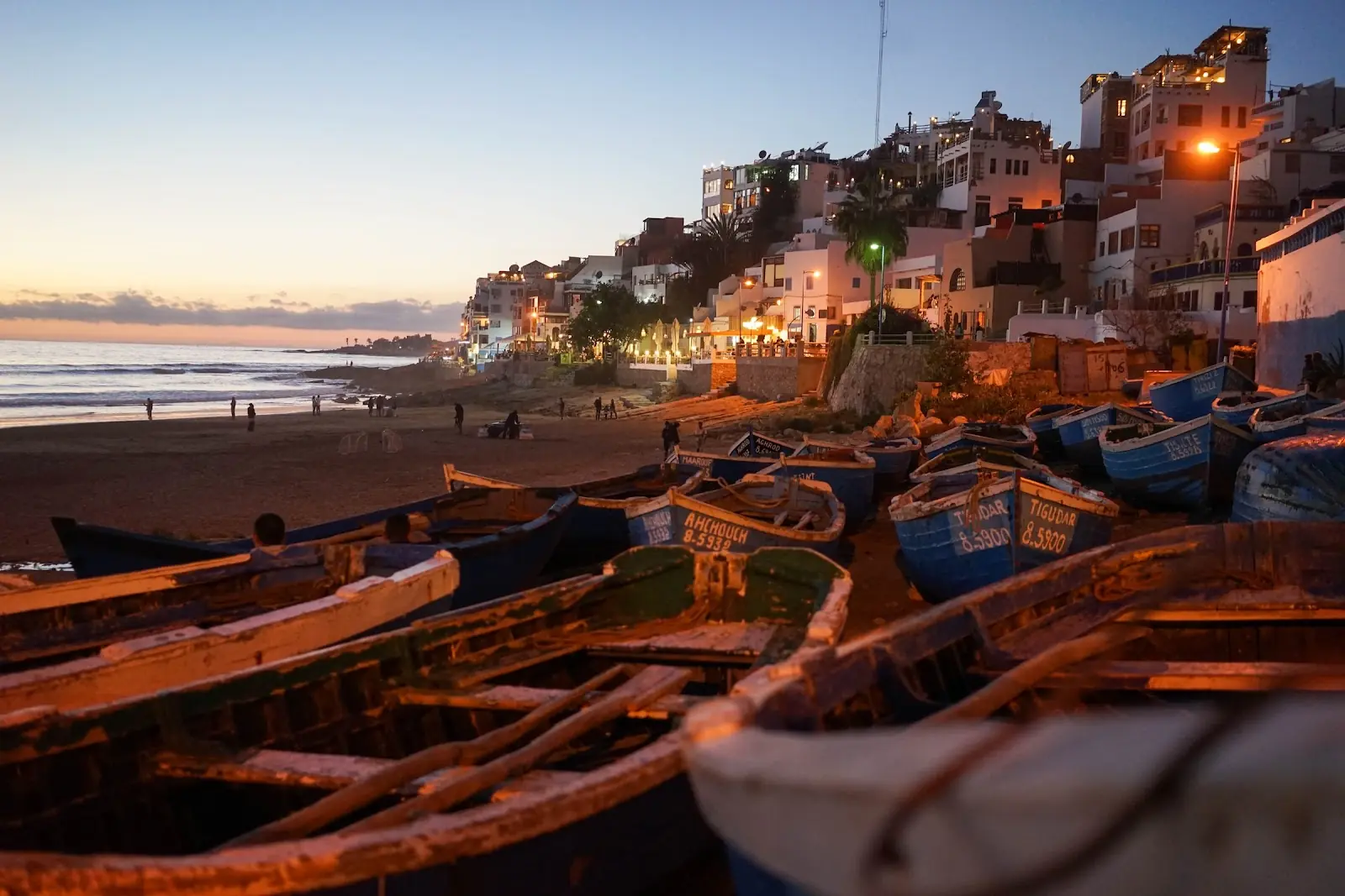 Sunset on a Moroccan beach, overlooking fishing boats and a small village.