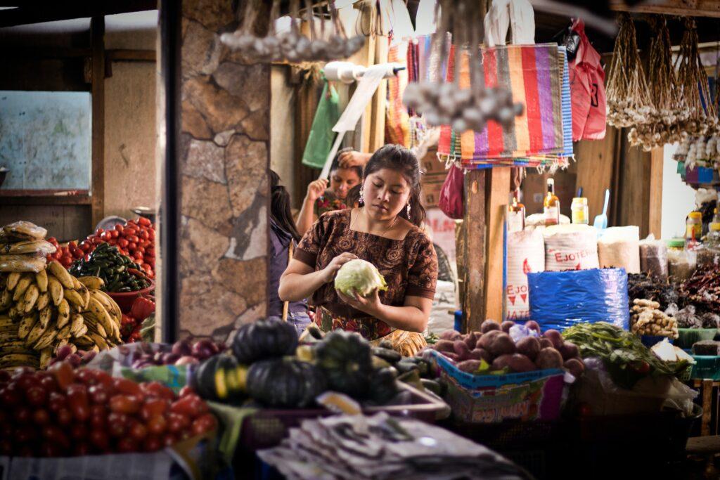 Woman sitting near vegetable stand in a market in Guatemala