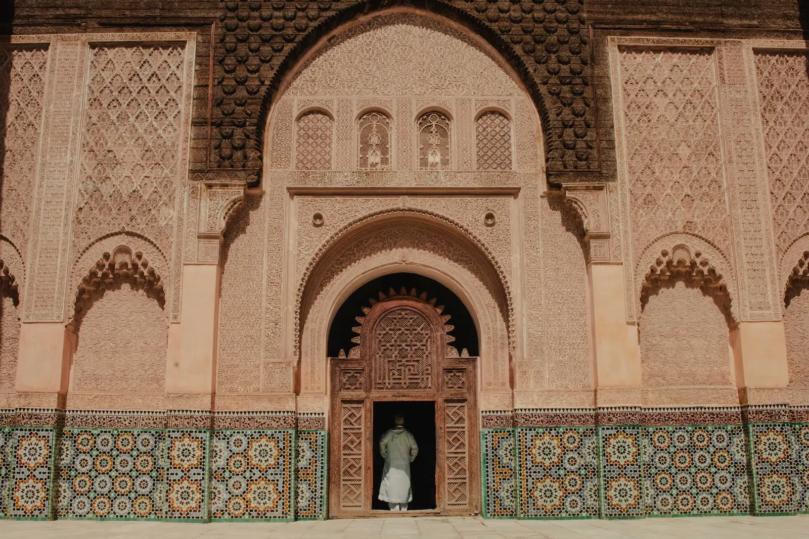 An ornate sandstone temple covered with green and yellow symmetrical tiles.
