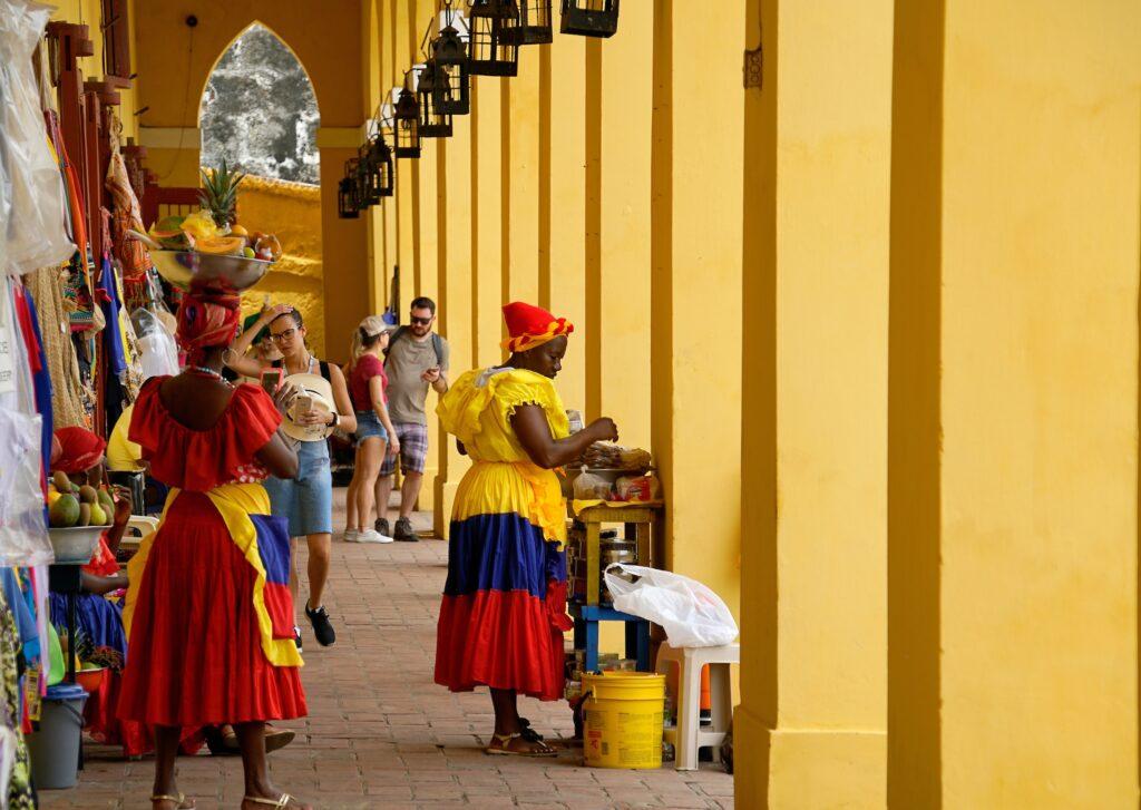 A colourful market with tourists and women in traditional dress. 