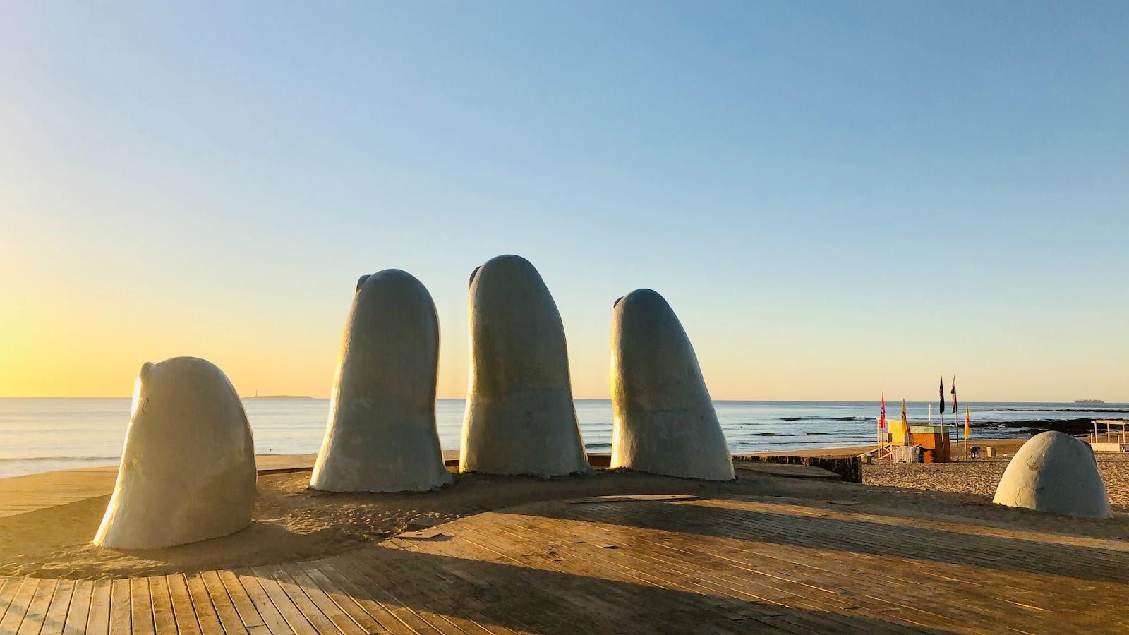 A Uruguayan 5 fingered statue sticking out of a beach.