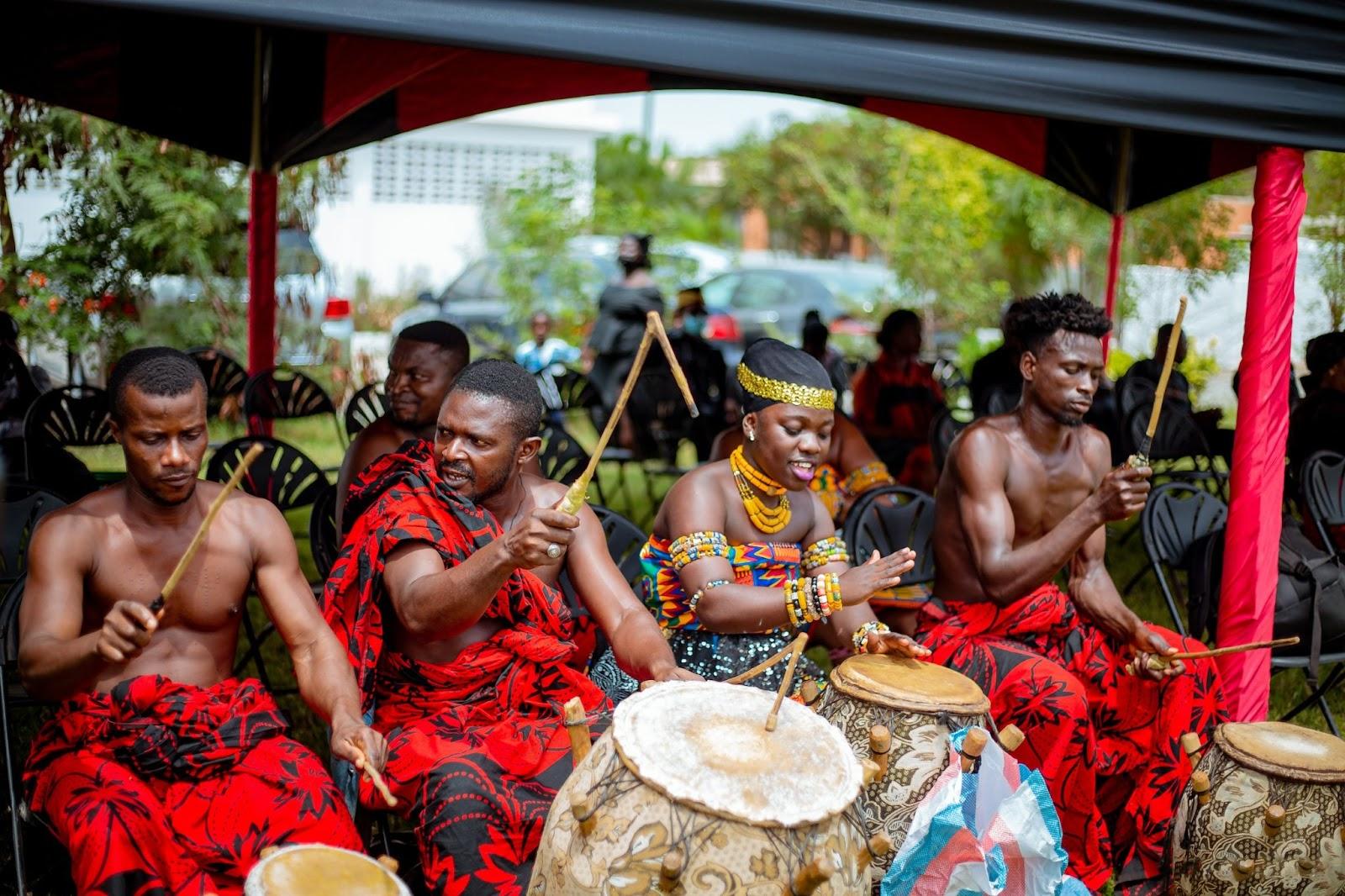 Traditional Ghanaian musicians dressed in red, playing the drums