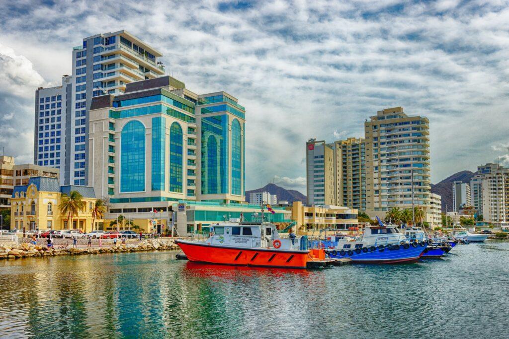 A colourful port next to a city skyline with mountains in the background.
