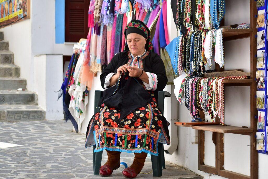 Traditionally dressed woman crafting in the street Karpathos Greece, Europe