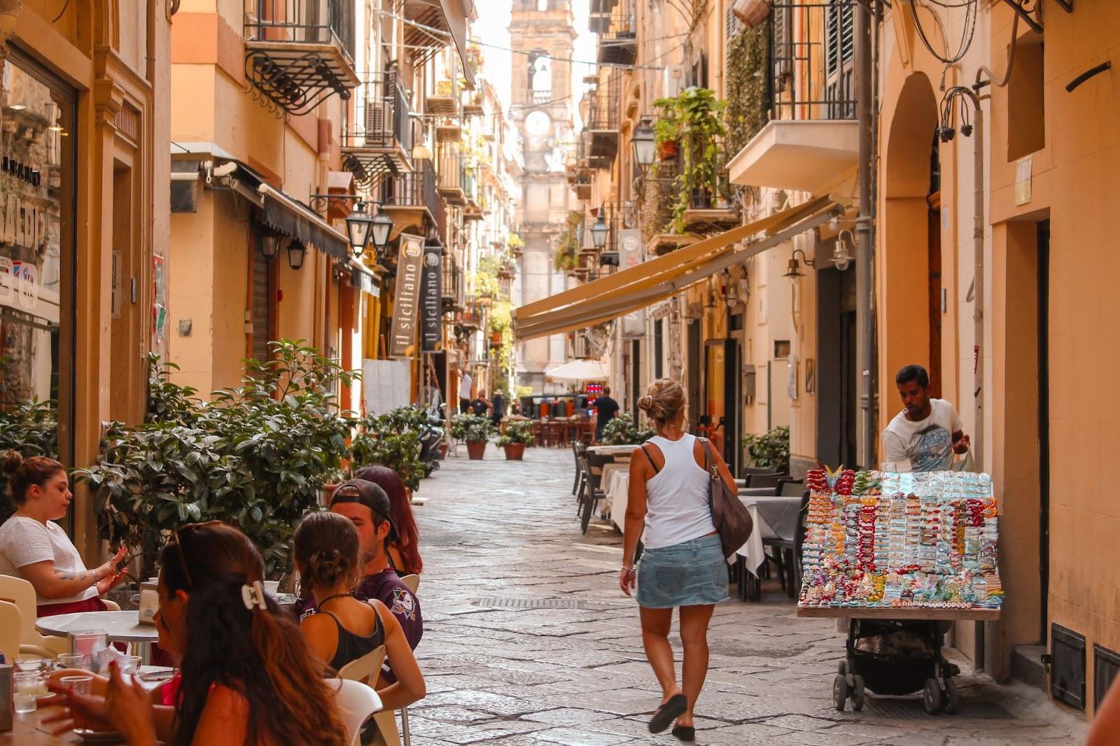 Lady walking away down a narrow cobbled street in Palermo Sicily, Europe