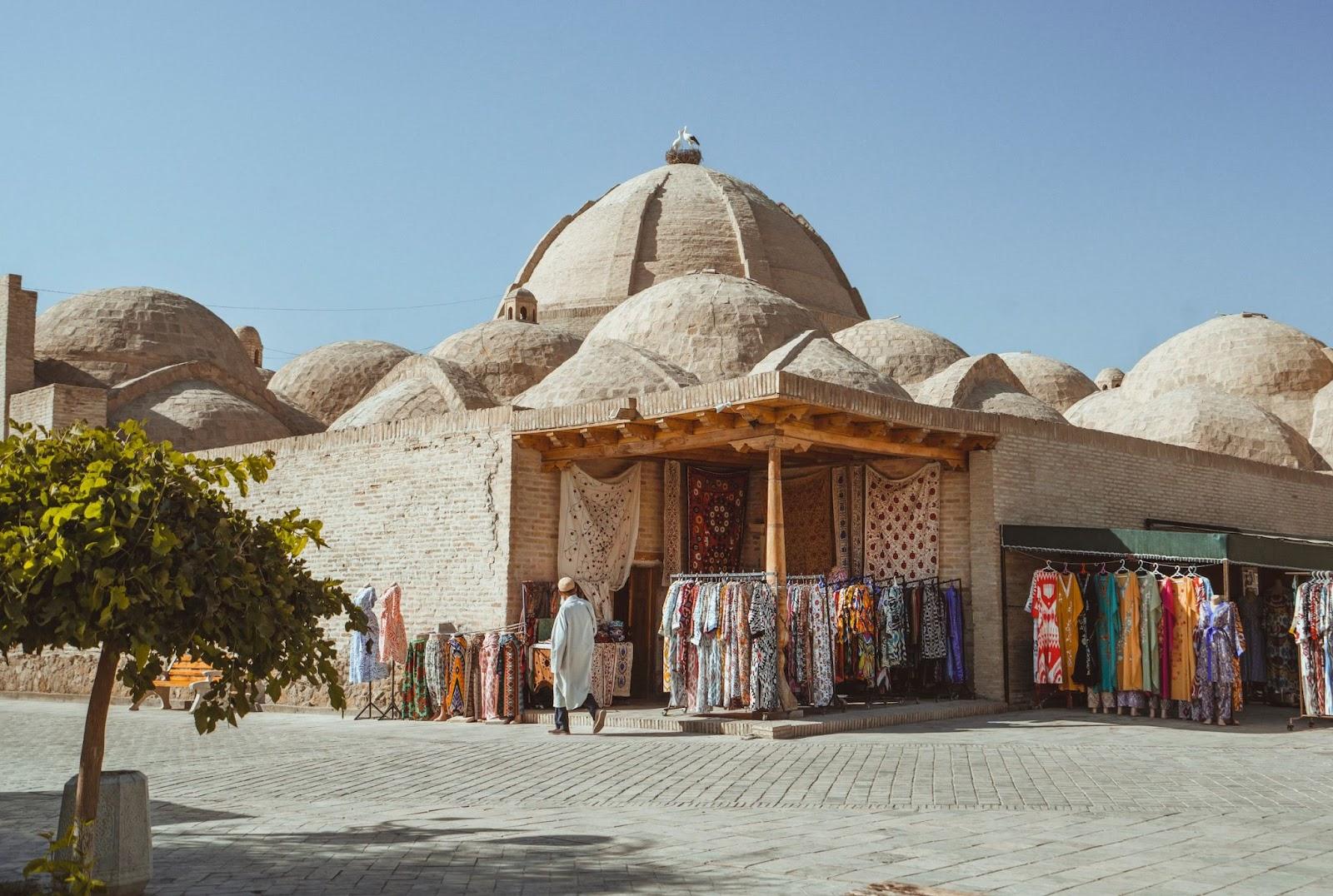 The Trading Dome Toqi Zargaron featuring a man walking past the bazaarz selling clothing.