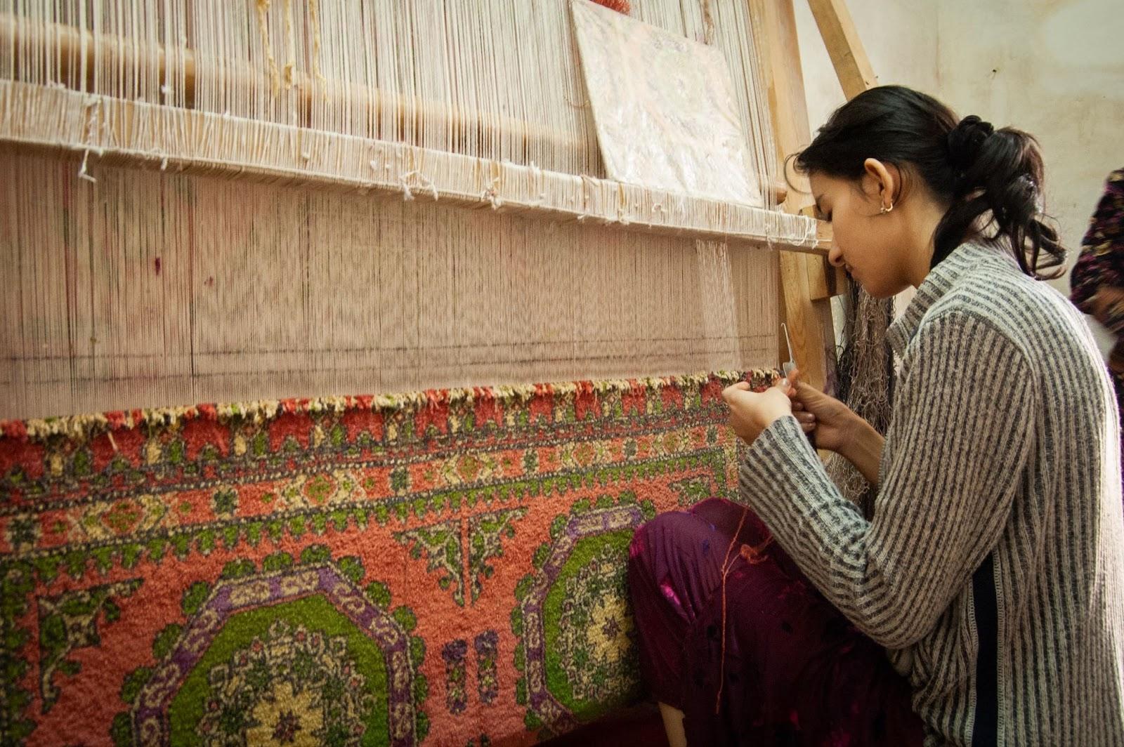 A Uzbekistani woman hand weaving a carpet
