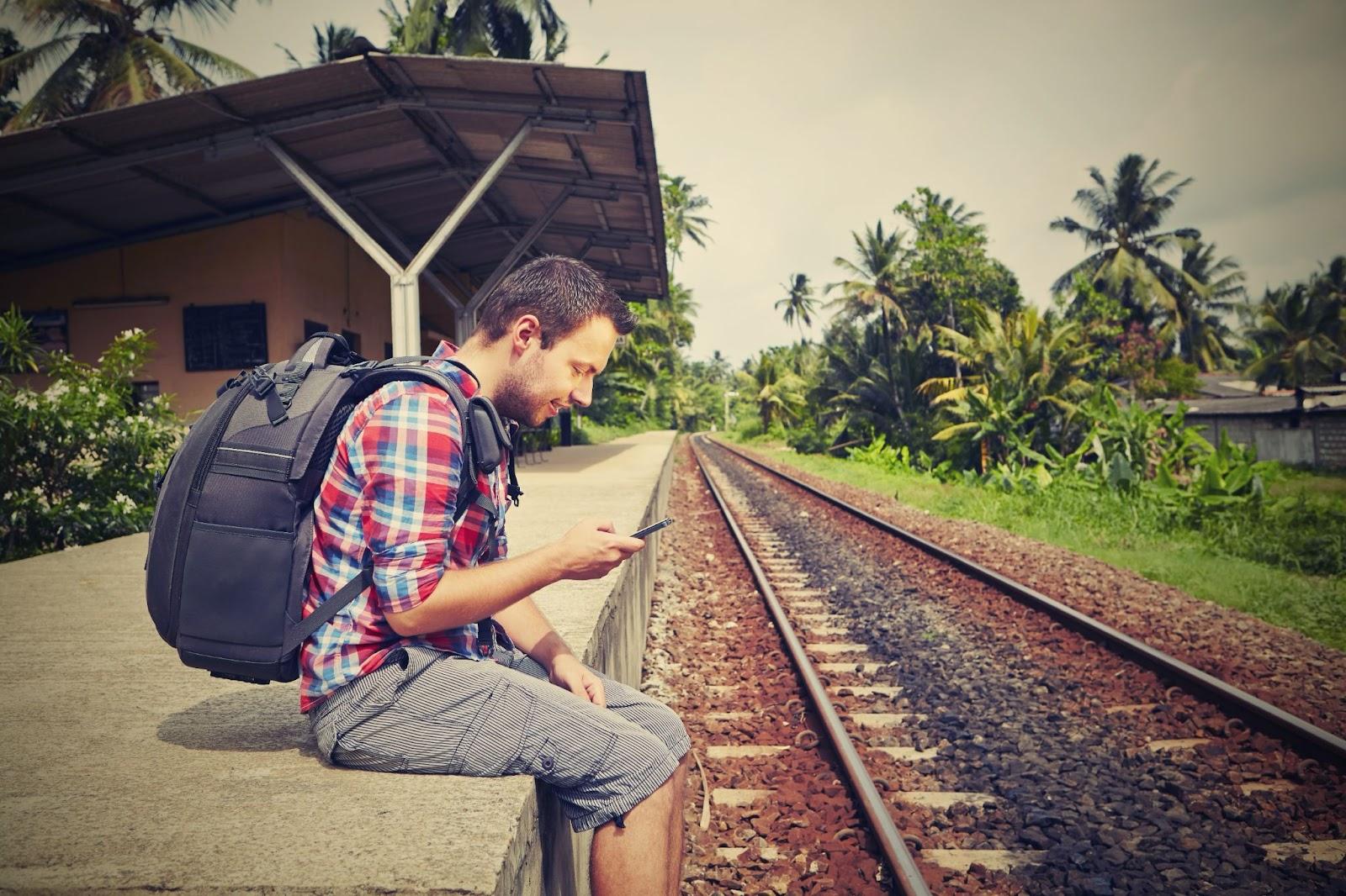 Young traveler with mobile phone on the railway platform