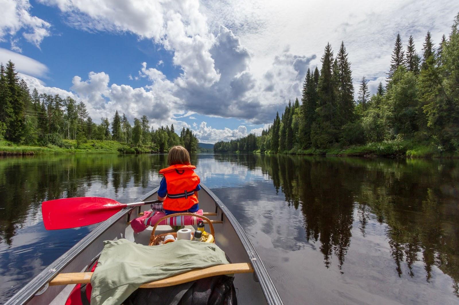 A women sits in a canoe on a river in Sweden. 
