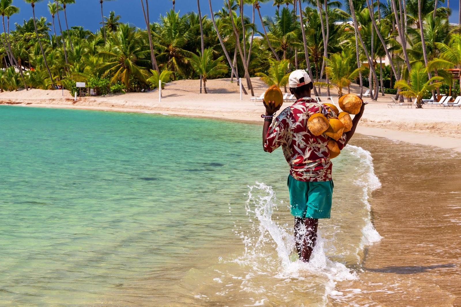 Coconut seller walking by the sea in the famous Juan Dolio Beach of Dominican Republic