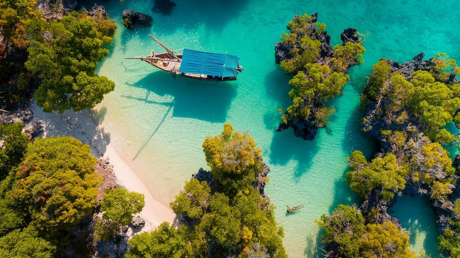 A birds eye view of a secluded beach and fishing boat. 