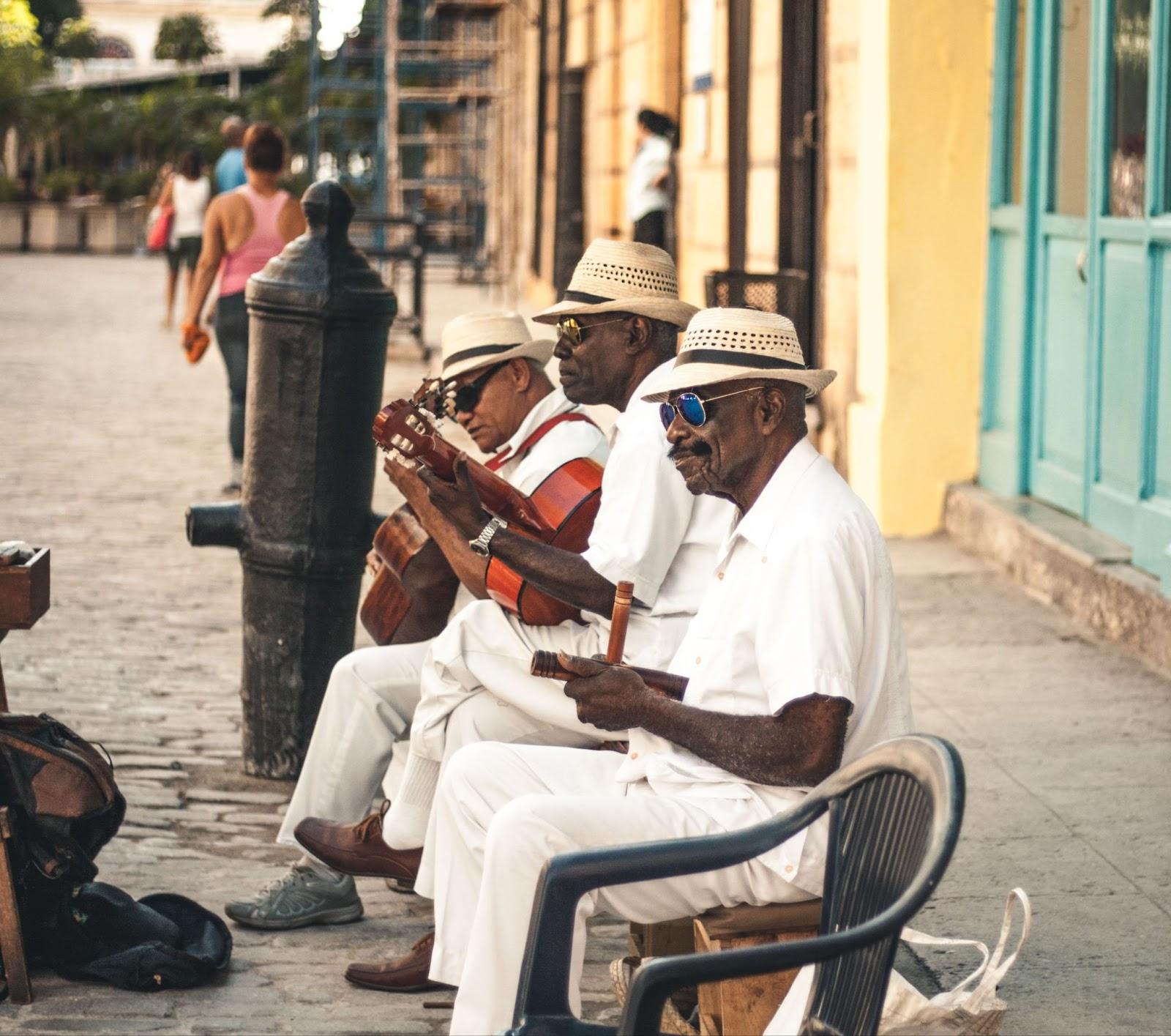 Local Cubans playing the guitar on a bench.