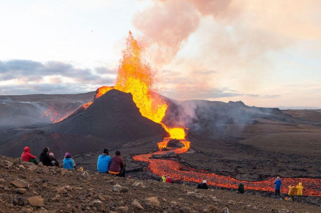 People watching magma exploding from a volcano in Iceland.