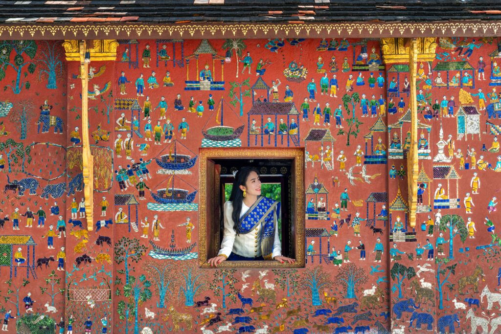 Asian girl enjoy travel in Wat Xieng Thong temple one of the most famous attraction place in Luang Prabang, Laos.