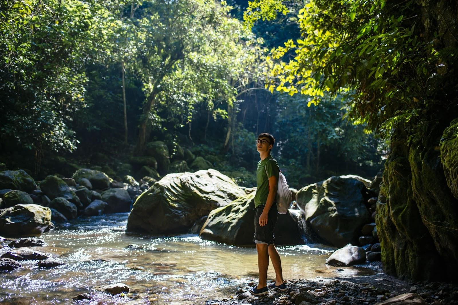 Young traveller is walking along a jungle stream in the amazon forest.