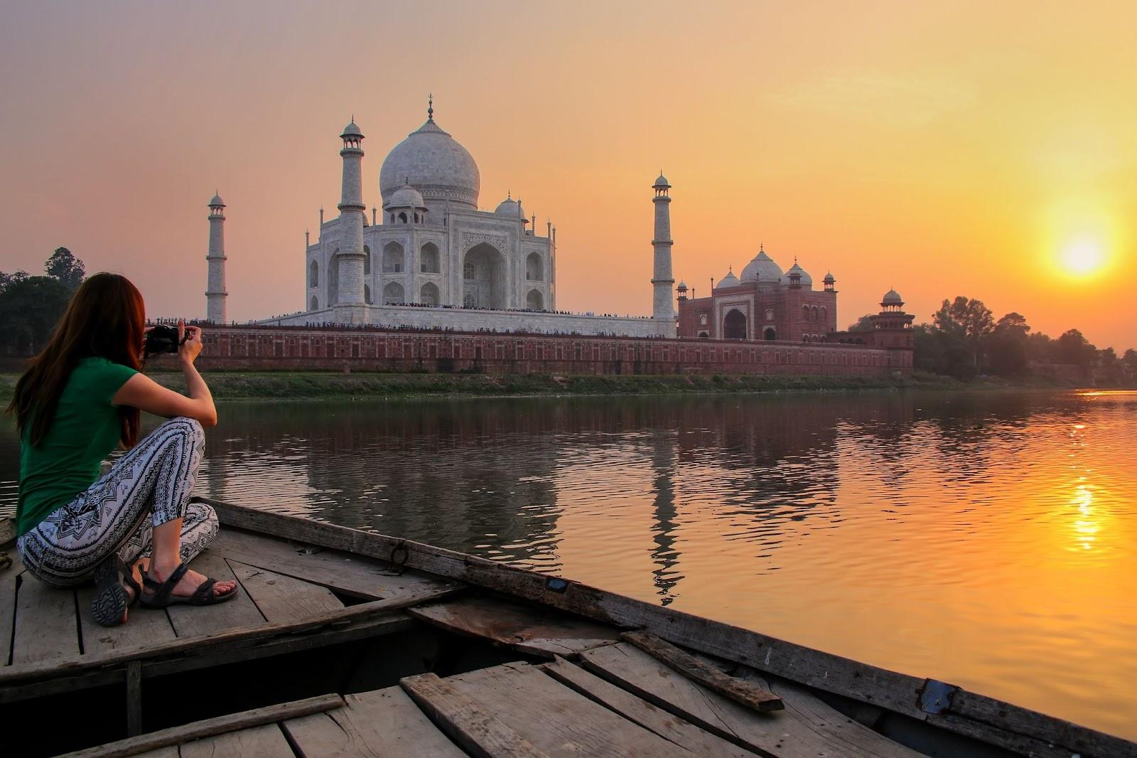 Woman watching sunset over Taj Mahal from a boat, Agra, India.