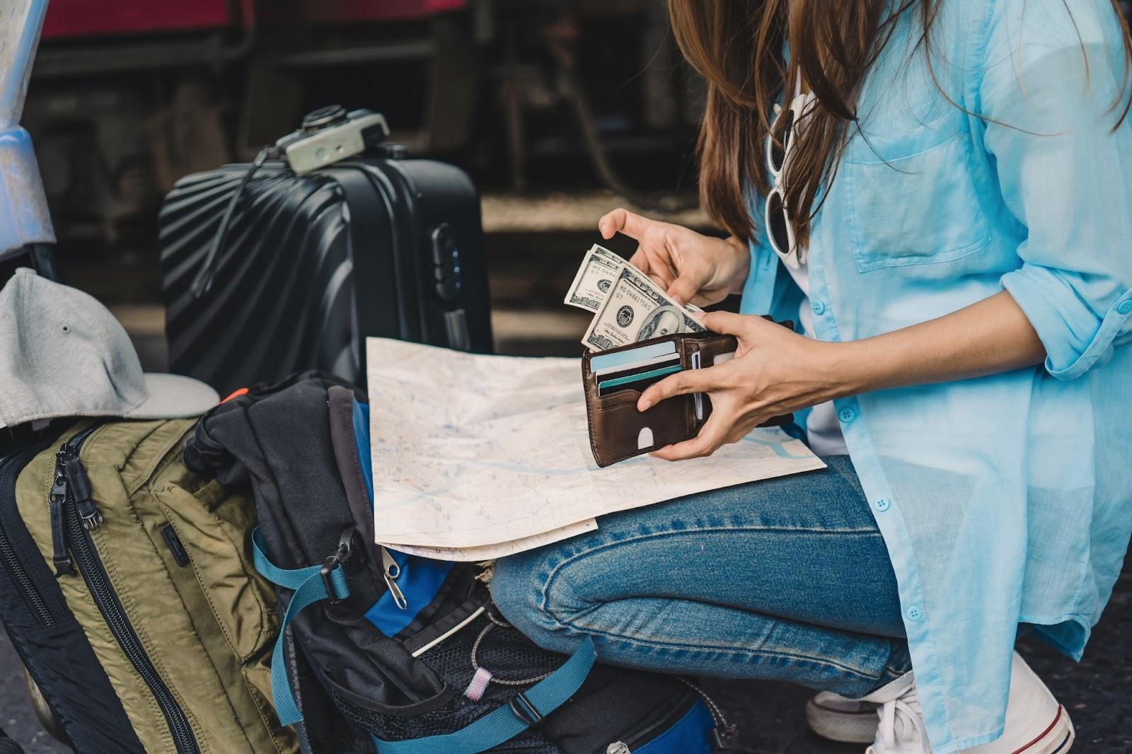 Woman traveller with a backpack counting cash she's travelling with in the open