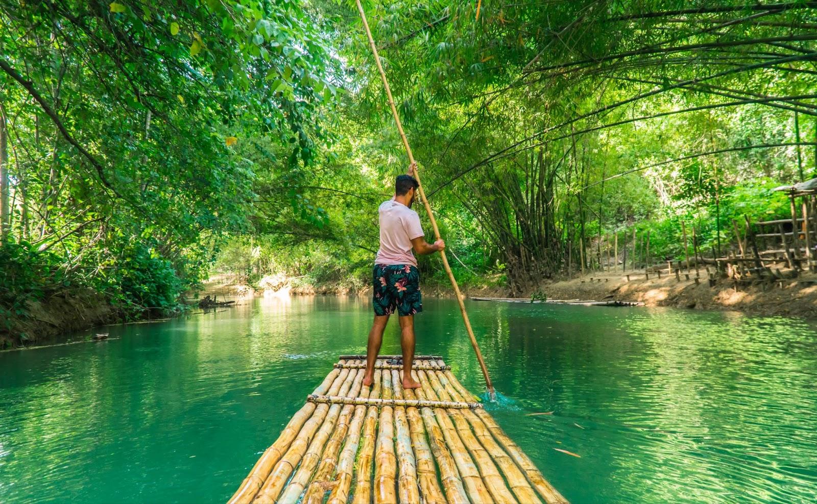 Landscape shot of man (tourist) rowing bamboo raft, whilst on cruise on vacation in Montego Bay, Jamaica, Caribbean.