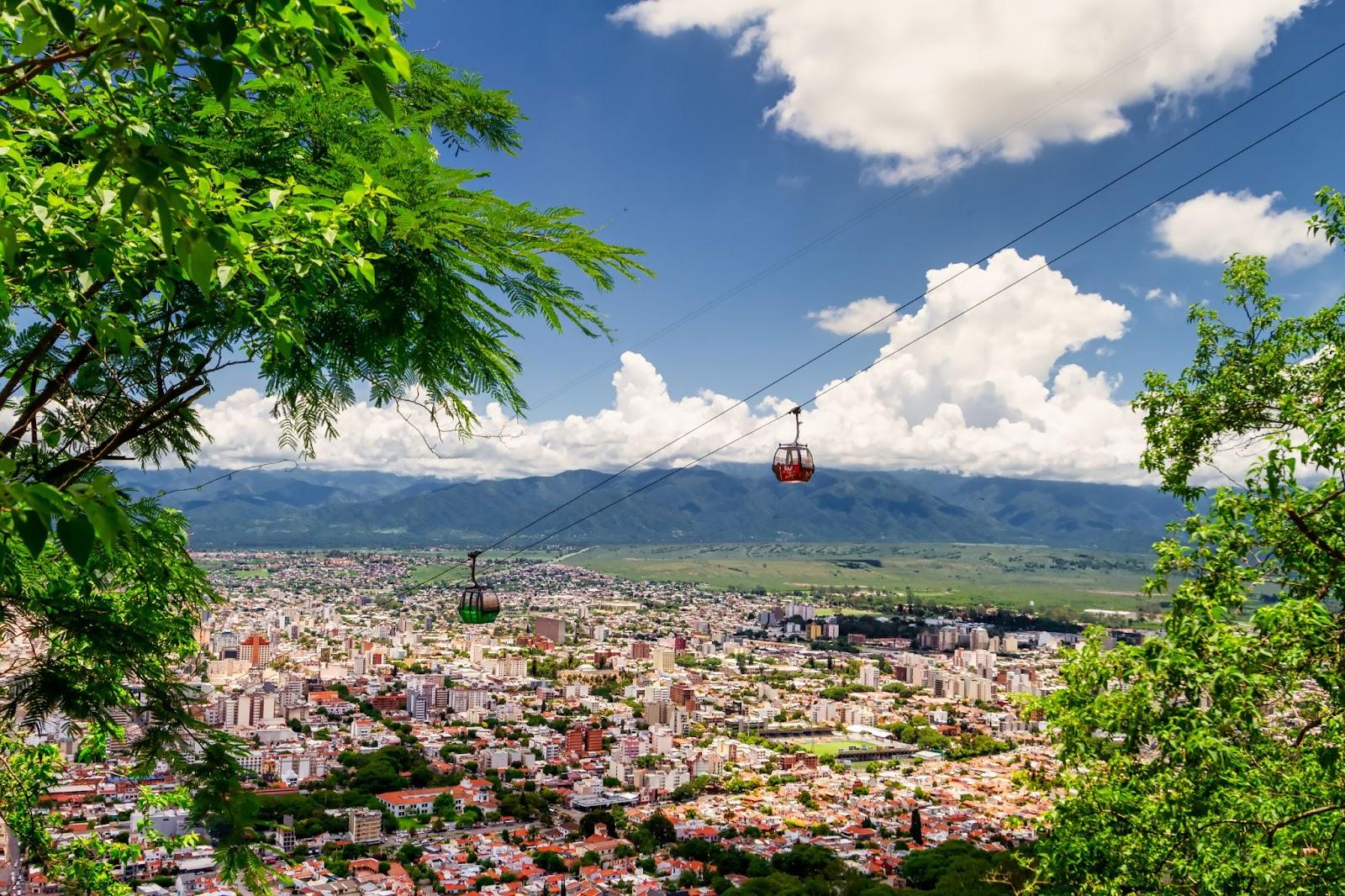 Salta, Argentina Two cable car cars cross each other on the San Bernardo hill with the capital of the northern province in the background