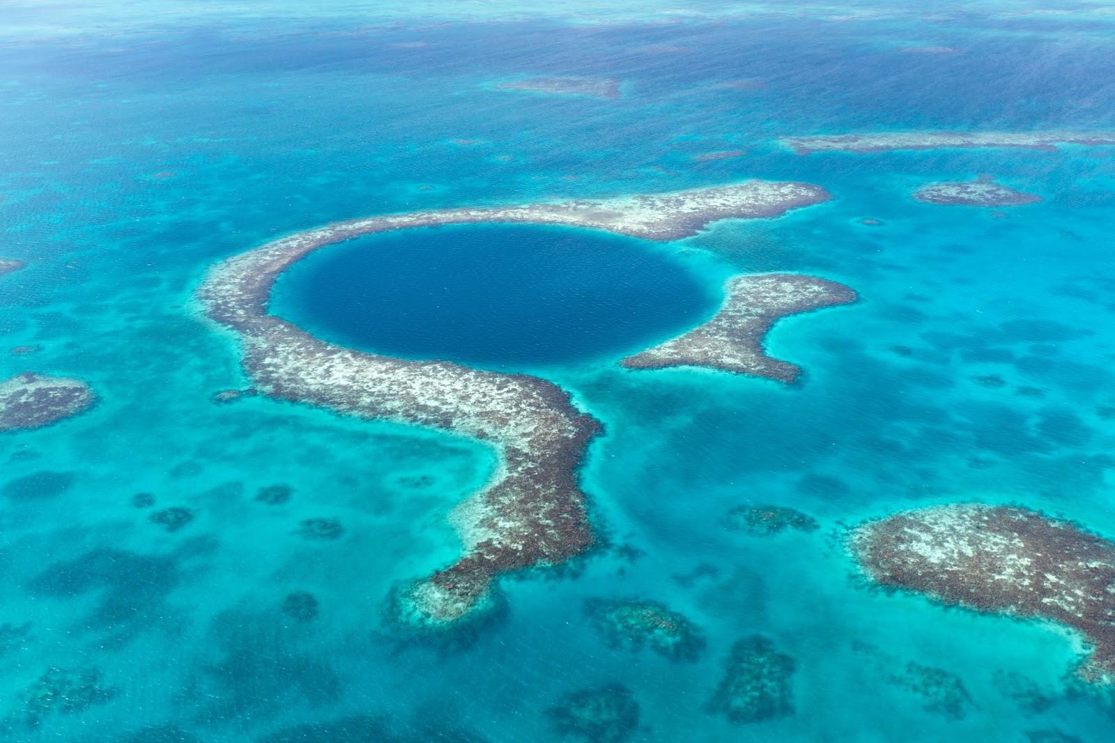 An aerial view of the coral reef and deep cave that make up the famous diving spot of the Blue Hole in the Caribbean Ocean off the coast of Belize.
