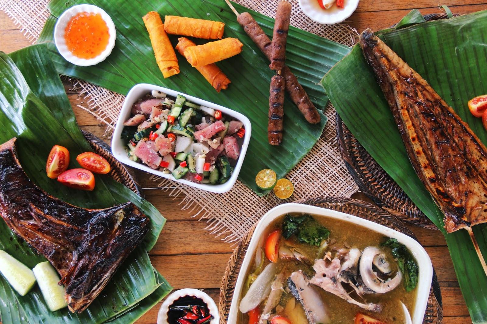 Table Set of Filipino Food Sinigang, Kinilaw, Shanghai, Longganisa, Grilled Tuna, plus Condiments on Banana Leaf