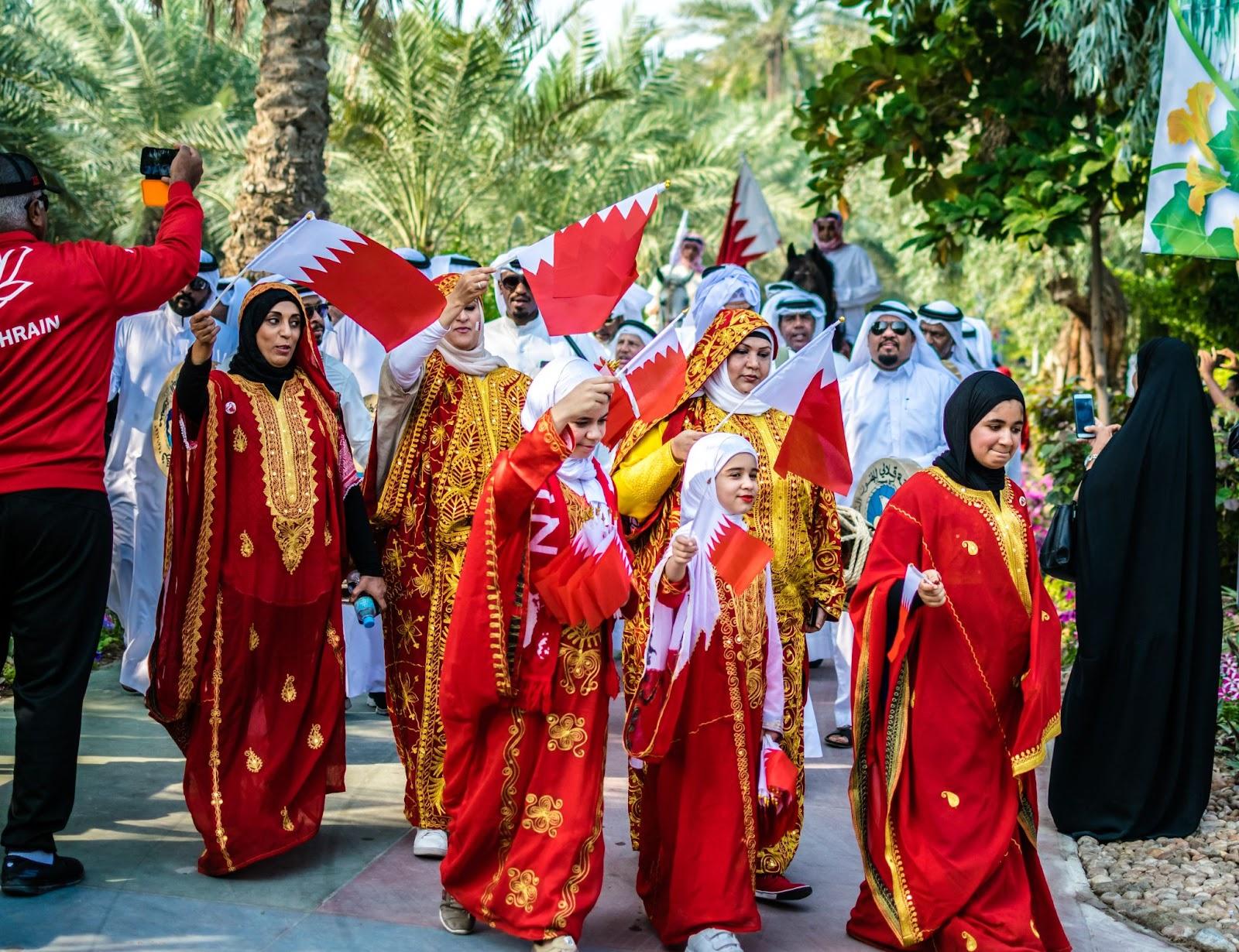 A group of people in their traditional coloured dresses walks on the street during national day parade celebration in Bahrain