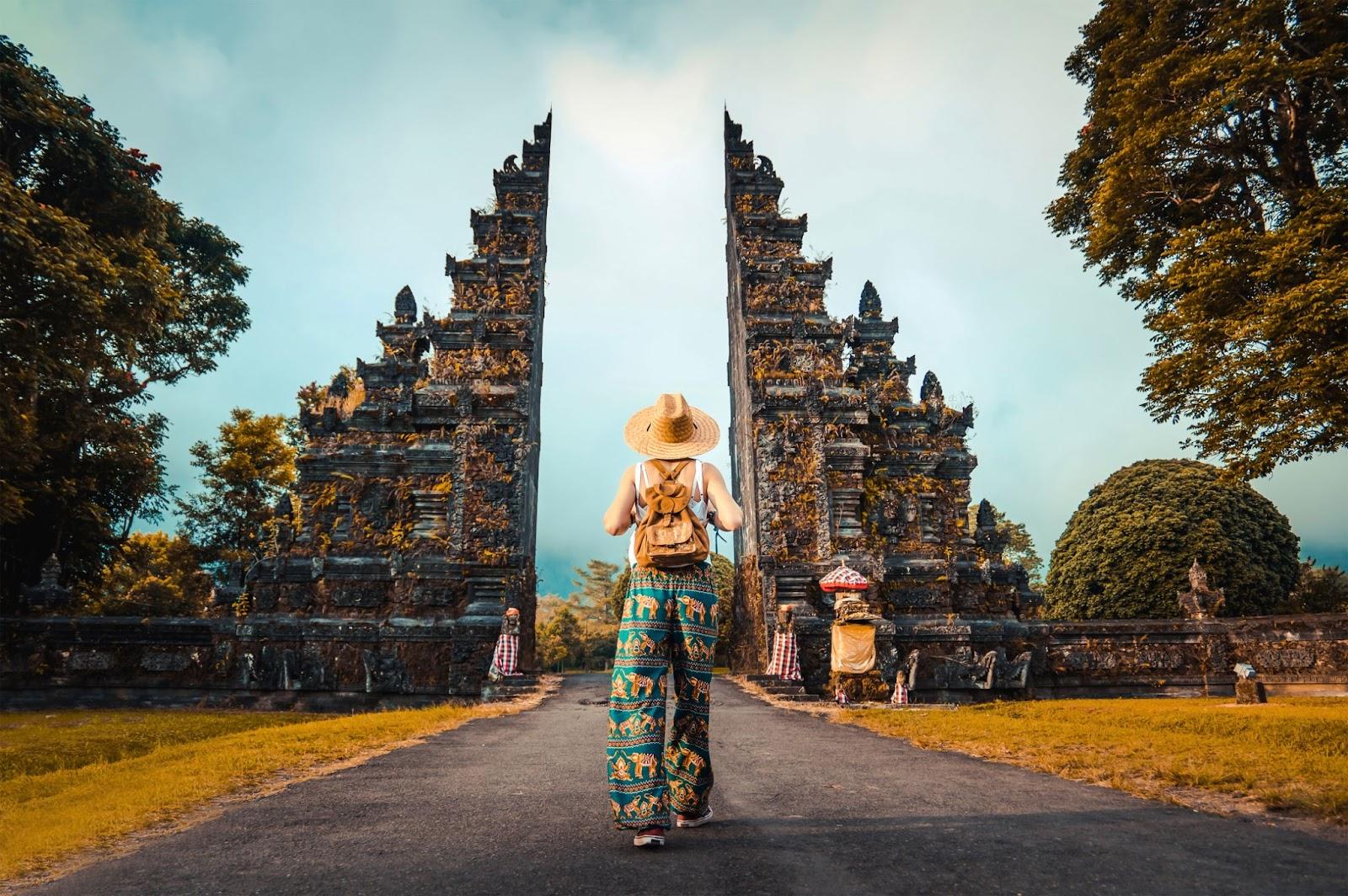 A women stands next to an Indonesian temple. 