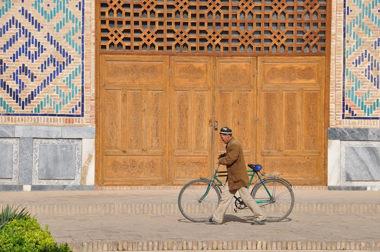 Uzbekistan man pushing bike