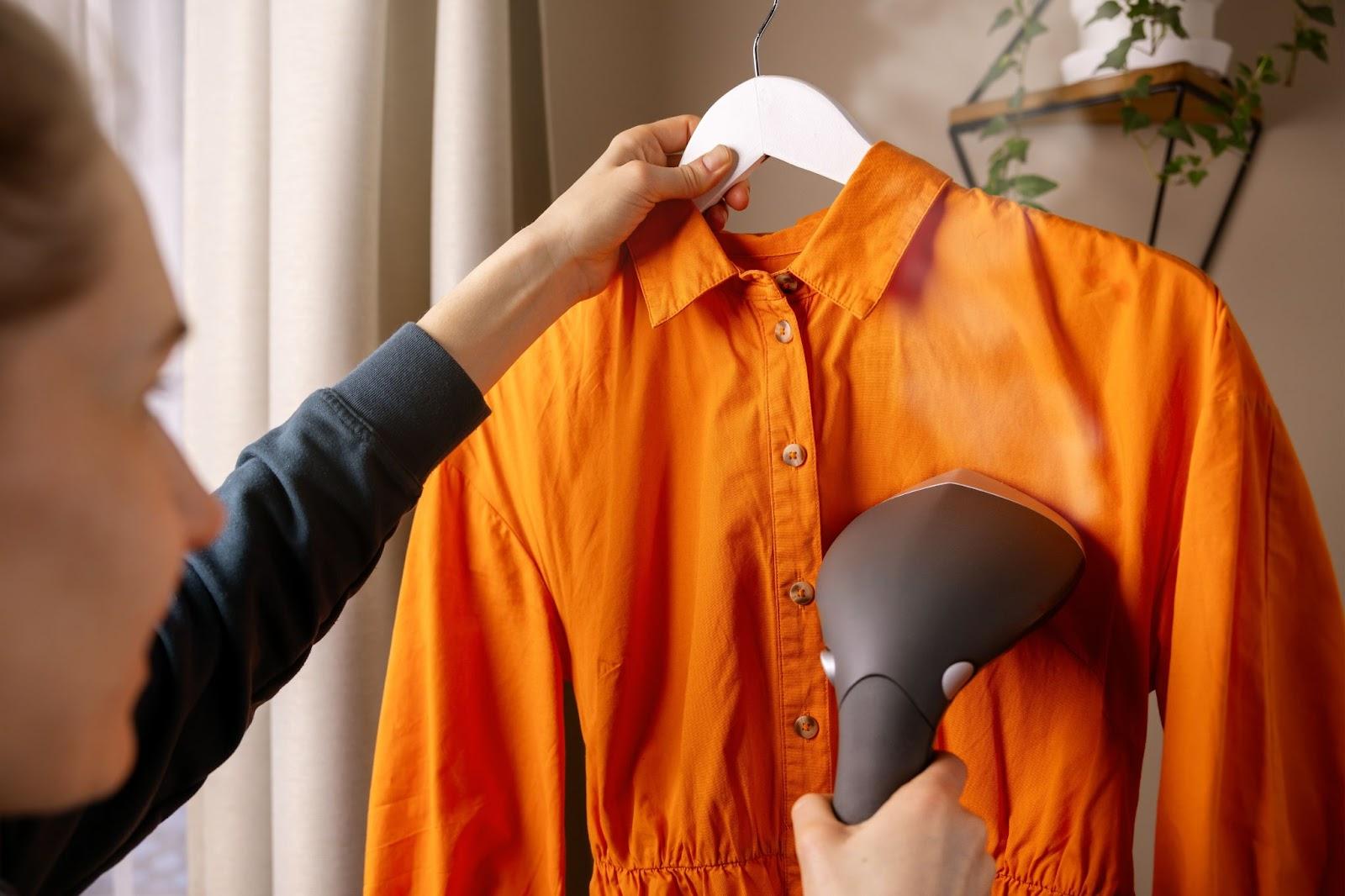 woman ironing dress with clothes steamer.