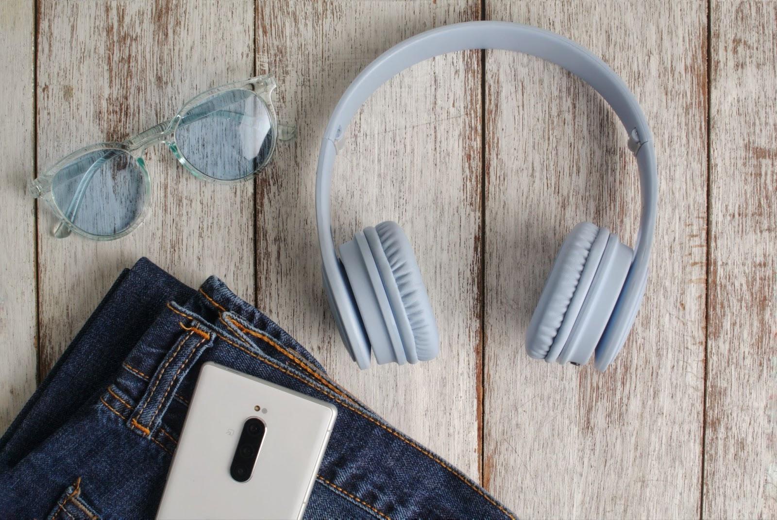Blue and white lifestyle theme in flatlay concept. Must have item for daily life: smartphone, headphone, jeans and sunglassess