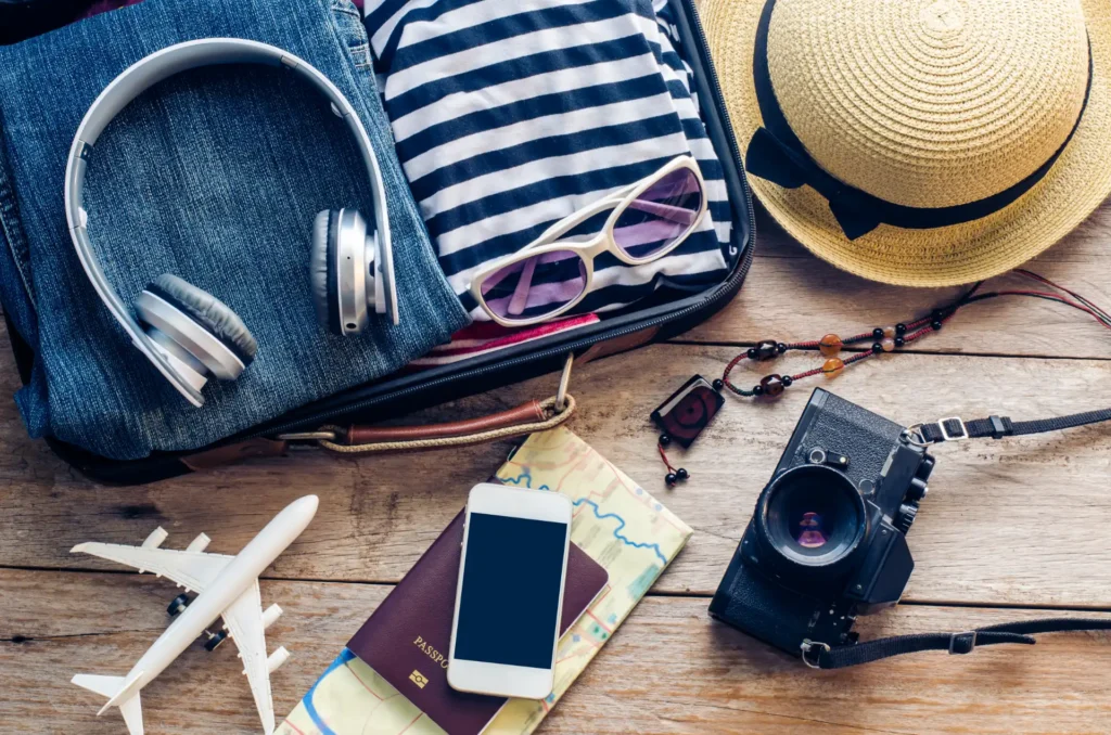 Clothing traveller's passport, wallet, glasses, smart phone devices, on a wooden floor in the luggage ready to travel.