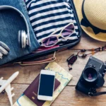 Clothing traveller's passport, wallet, glasses, smart phone devices, on a wooden floor in the luggage ready to travel.