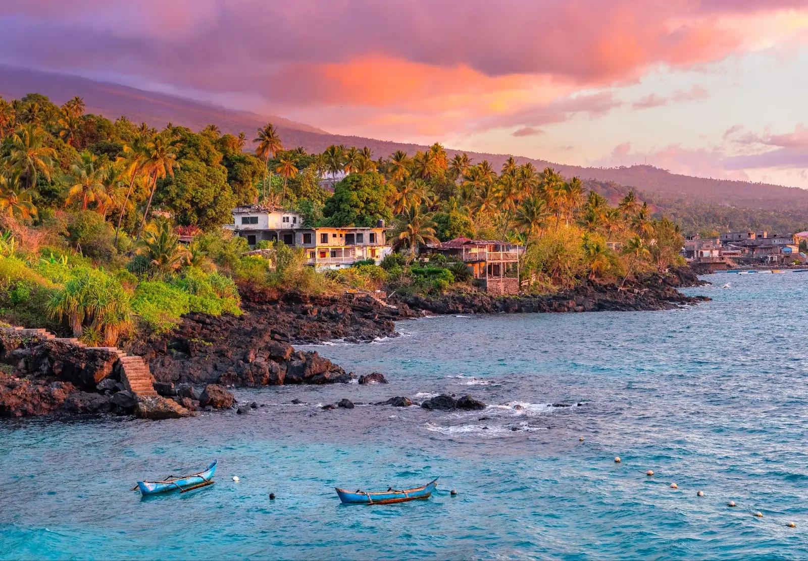 Canoes lying in the sun in the holiday seaside resort on the island of Grand Comore, Comoros. Beautiful light of the setting sun in the sea.