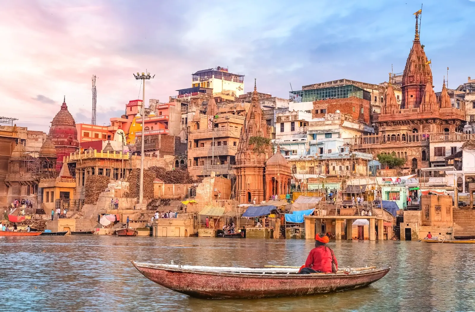 Ancient Varanasi city architecture at sunset with view of sadhu baba enjoying a boat ride on river Ganges