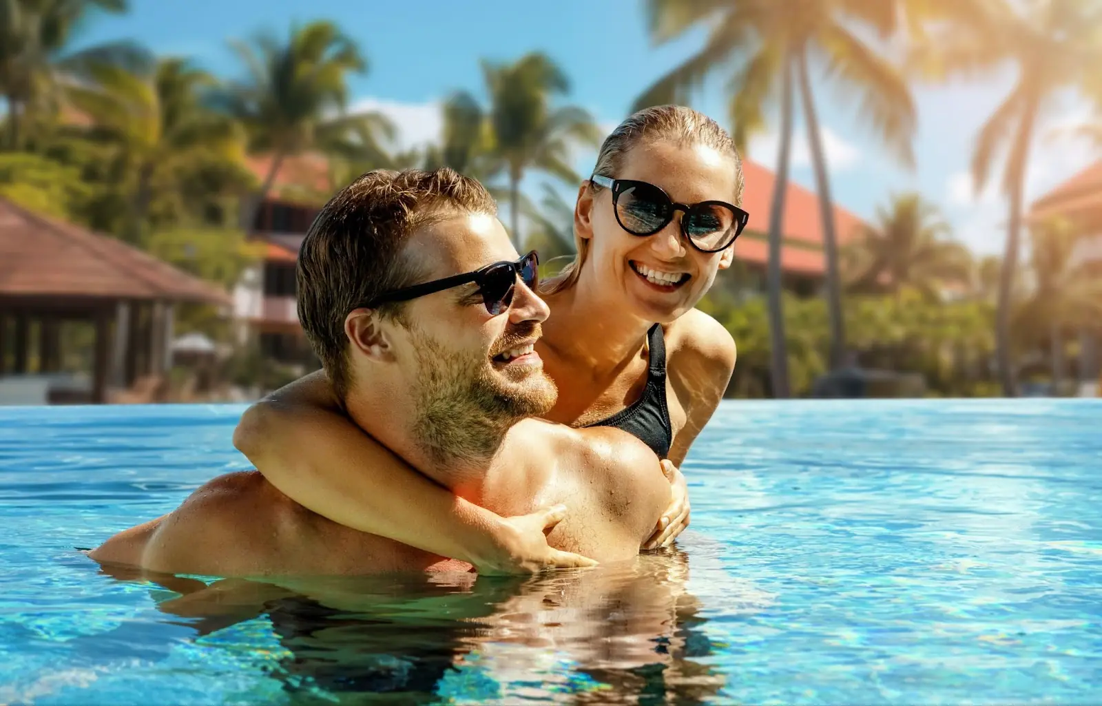 smiling happy couple having fun together in resort swimming pool