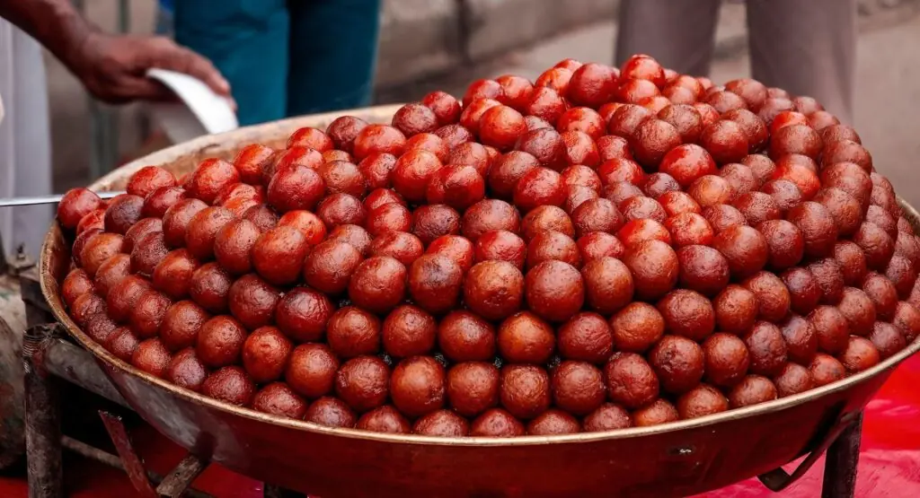 Large tray stacked with gulab jamun balls, the sticky sweet rosewater berry treat found all over the Indian subcontinent. This is in an Old Delhi bazaar.