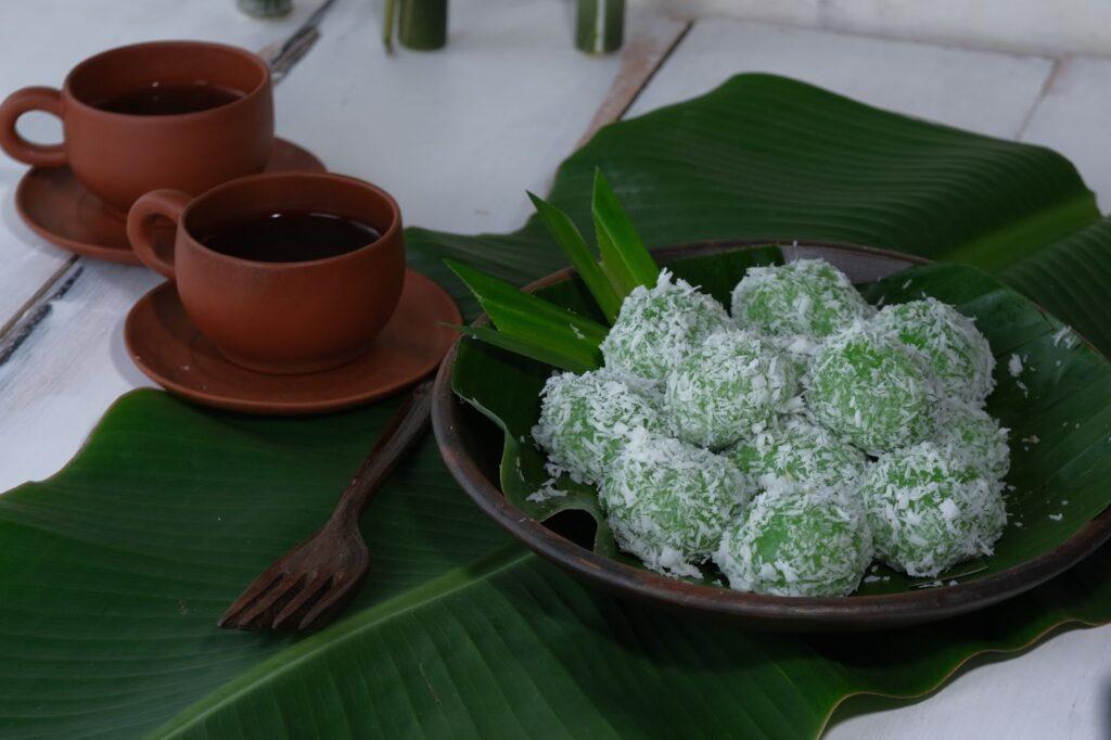 This special snack is called klepon, the color is green, there is brown sugar inside and the outside is wrapped with grated coconut. Arranged on a pottery plate covered with banana leaves