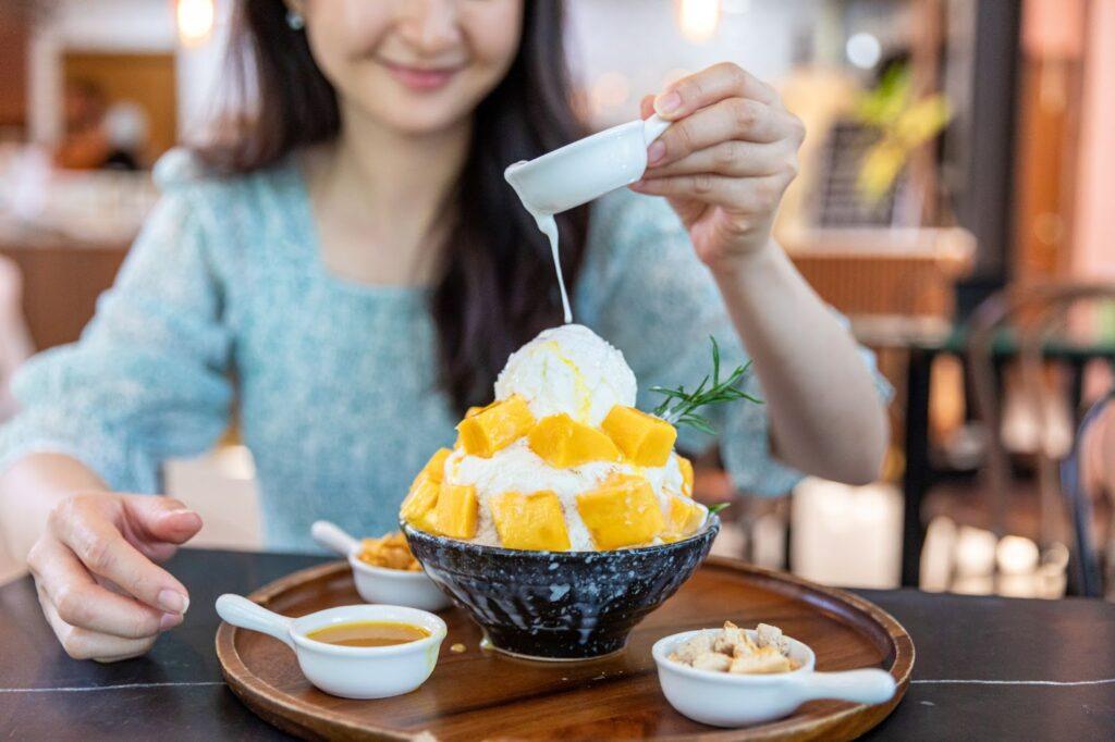 Shaved ice dessert with mango slices. Served with vanilla ice cream and whipped cream. Sweet dessert in Korean style. Local name, Bingsu.