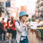 Happy young adult asian foodie woman backpack traveller eating asia dessert. People traveling with lifestyle outdoor at China town street food market. Bangkok, Thailand
