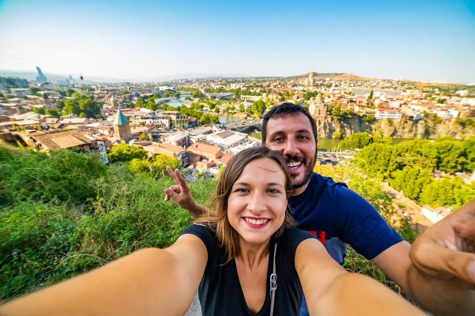Couple taking selfie in Tbilisi with aerial view of old Tbilisi. They got their travel money and best exchange rate at Manor FX 