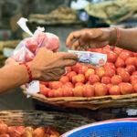 Male buyer paying with cash after buying tomatoes at the Port Louis market in Mauritius.