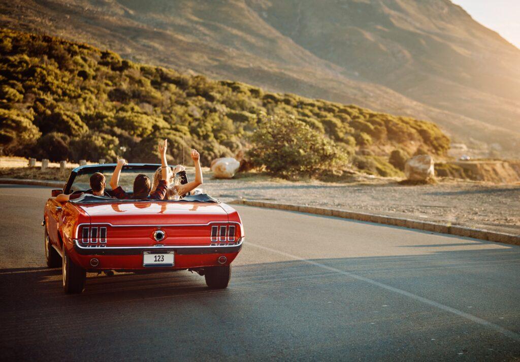 Travel, freedom and friends in car for road trip by sunset for countryside vacation or holiday. Adventure, nature and group of people in convertible for driving to weekend destination in Ireland.