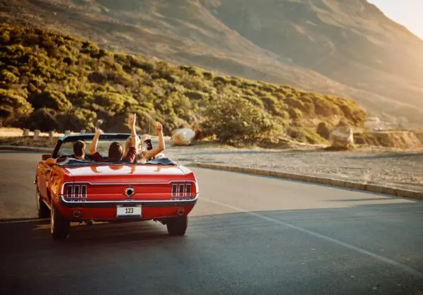 Travel, freedom and friends in car for road trip by sunset for countryside vacation or holiday. Adventure, nature and group of people in convertible for driving to weekend destination in Ireland.
