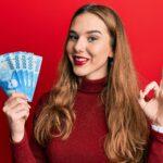 Young blonde woman holding 10000 chilean peso.